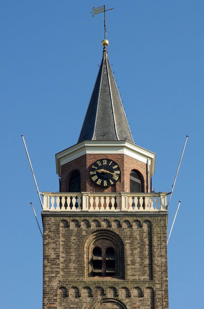 De toren van de Grote Kerk (Laurentiuskerk) in Rijnsburg tegen een blauwe lucht — monumentale dorpskerk en herkenbaar baken in de gemeenschap